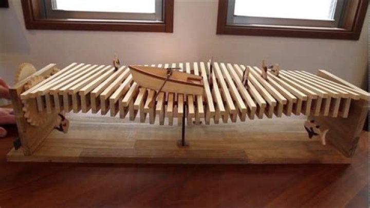 Kinetic wooden wave sculpture with a little boat and jumping fish